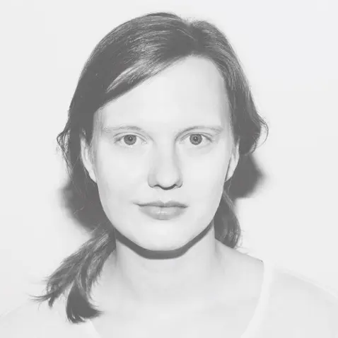 Portrait photo of Antonia Gersch in a light-colored shirt with her hair tied back. The photo is a black and white portrait by photographer Katja Stempel.